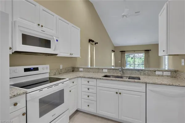 a kitchen with granite countertop white cabinets white stainless steel appliances and sink
