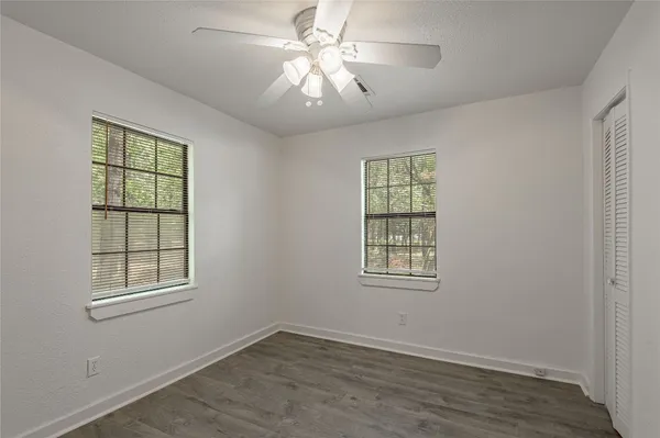 a view of an empty room with a window and wooden floor