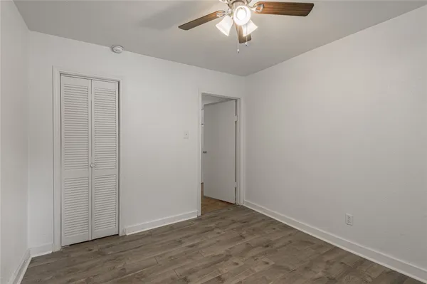 an empty room with wooden floor chandelier fan and closet area
