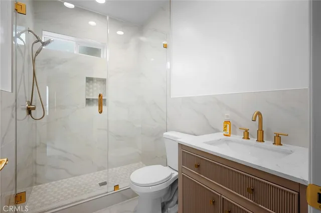 a bathroom with a shower sink vanity mirror and toilet