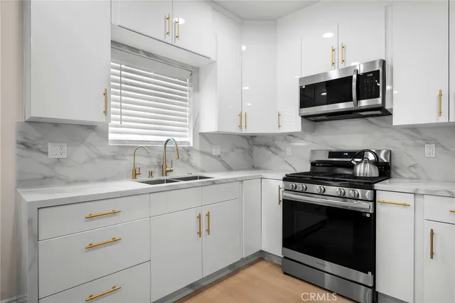 a kitchen with stainless steel appliances a stove a sink and cabinets