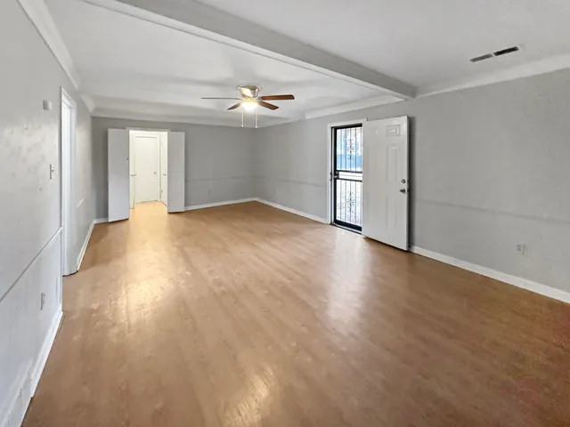 a view of empty room with wooden floor and fan