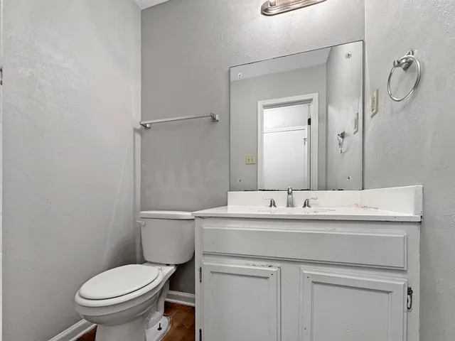 a bathroom with a granite countertop toilet sink and mirror