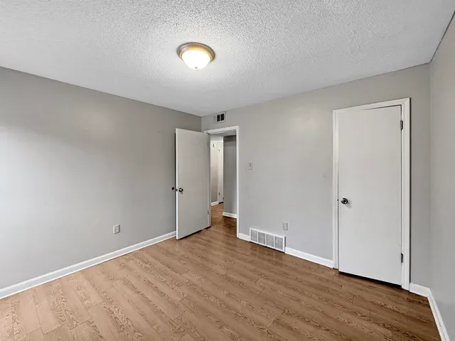a view of an empty room with wooden floor and closet