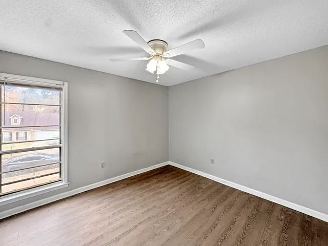 an empty room with a window and a fan