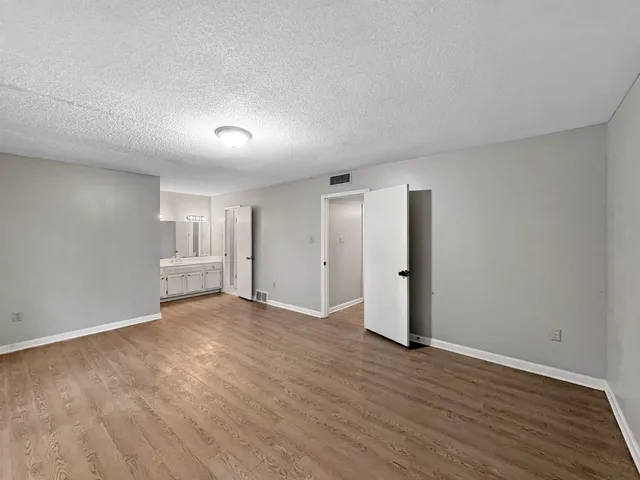 a view of an empty room with wooden floor and closet