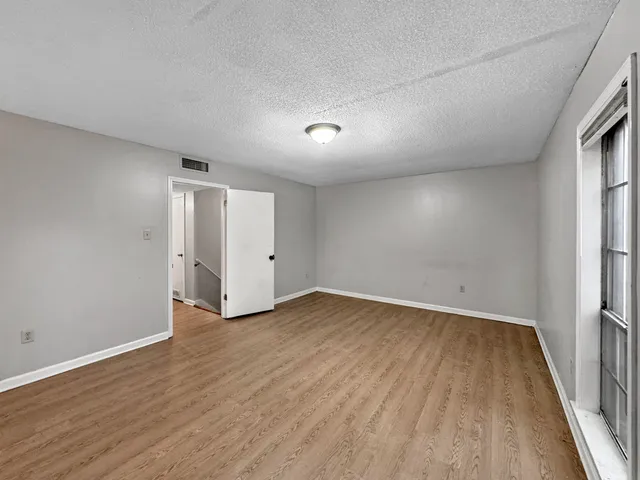 an empty room with wooden floor and windows