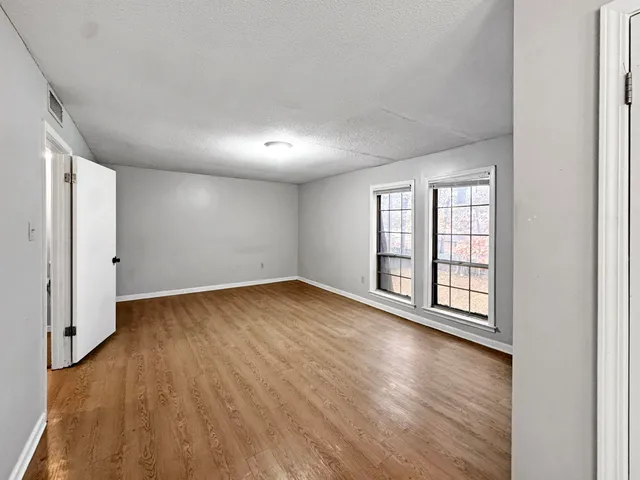 an empty room with wooden floor and windows