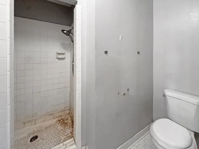 a white toilet sitting next to a shower