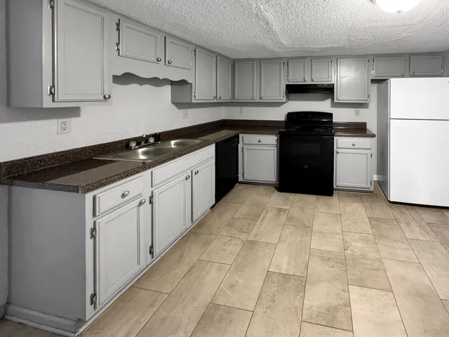 a kitchen with granite countertop a stove a sink and a refrigerator