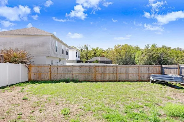 a view of a backyard with a large tree and wooden fence