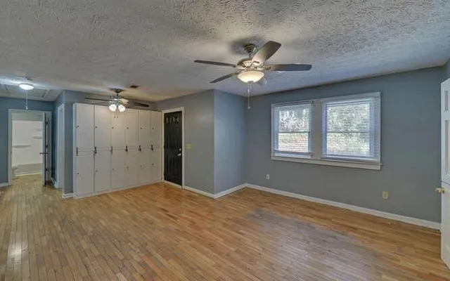 a view of a big room with wooden floor and a ceiling fan
