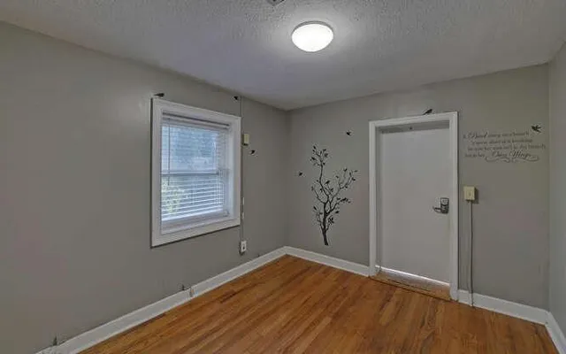 a view of an empty room with wooden floor and a window