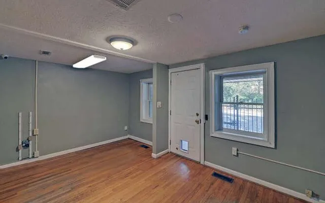 a view of empty room with wooden floor and fan