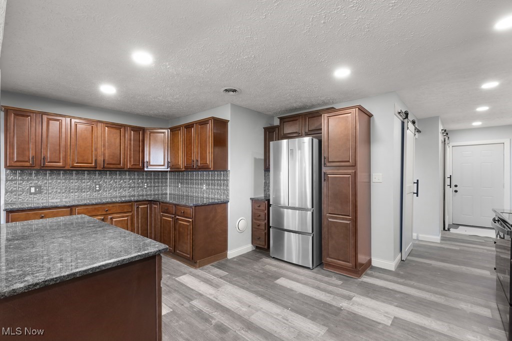 139 Patterson Road Weirton, WV 26062 - Photo 14 of 46 Kitchen featuring a barn door, freestanding refrigerator, recessed lighting, tasteful backsplash, and light wood-type flooring