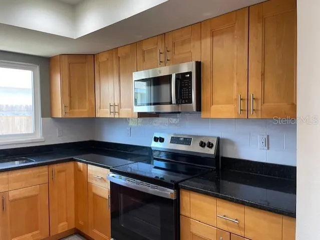 a kitchen with stainless steel appliances granite countertop wooden cabinets and a stove top oven