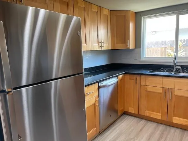 a kitchen with stainless steel appliances granite countertop a refrigerator and a sink