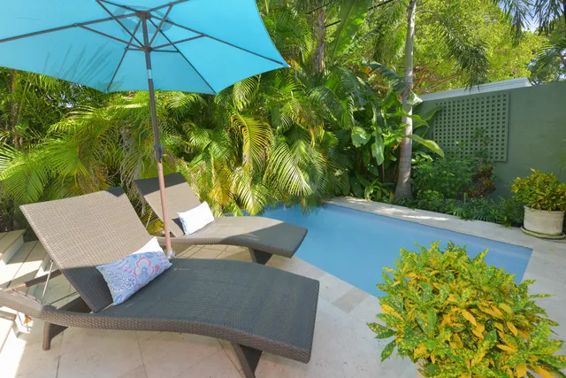 a view of a patio with couches table and chairs under an umbrella with wooden floor