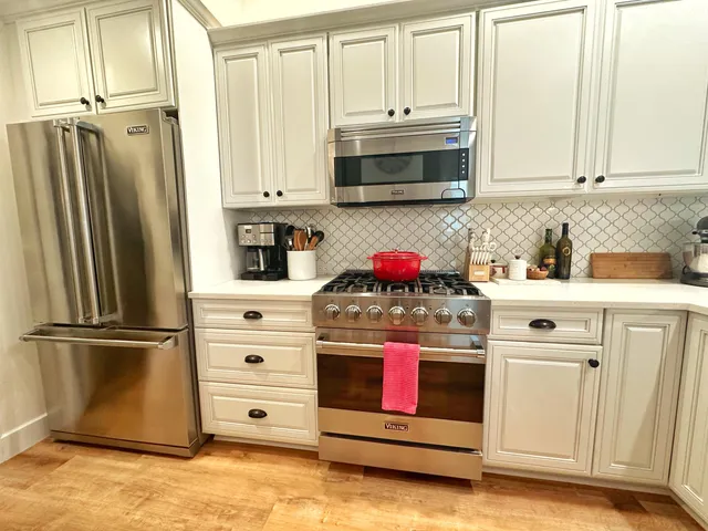 a kitchen with stainless steel appliances white cabinets and a refrigerator