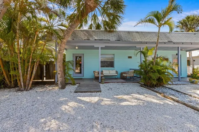 a view of a house with potted plants and palm trees
