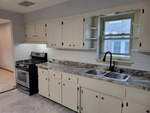 a kitchen with granite countertop white cabinets and stainless steel appliances