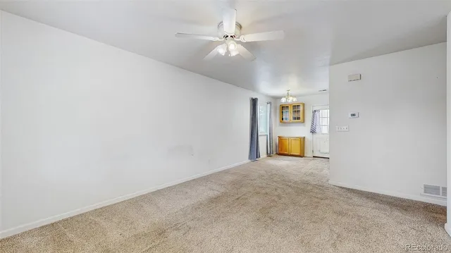 a view of a big room with chandelier fan and windows