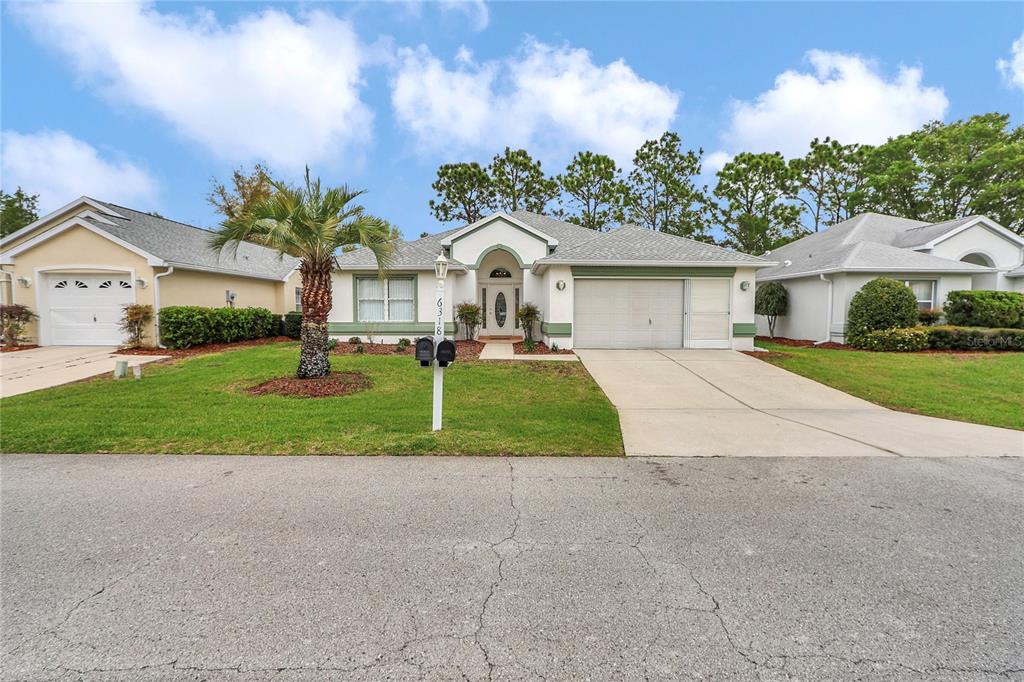6318 Southwest 117th Loop Ocala, FL 34476 - Photo 36 of 60 a front view of a house with a yard and potted plants