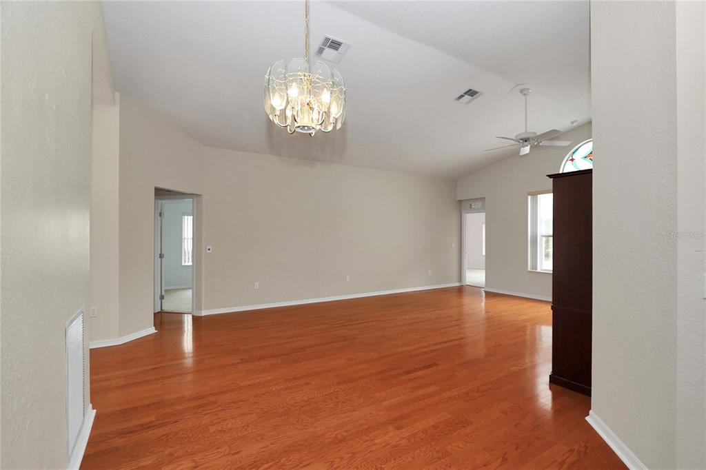 6318 Southwest 117th Loop Ocala, FL 34476 - Photo 8 of 60 an empty room with wooden floor and chandelier