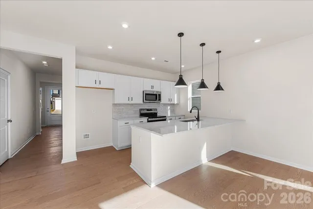 a kitchen with stainless steel appliances granite countertop a refrigerator a sink a stove and a refrigerator