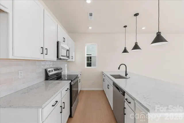 a kitchen with white cabinets and sink