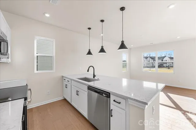 a kitchen with stainless steel appliances granite countertop a sink a window and wooden floor