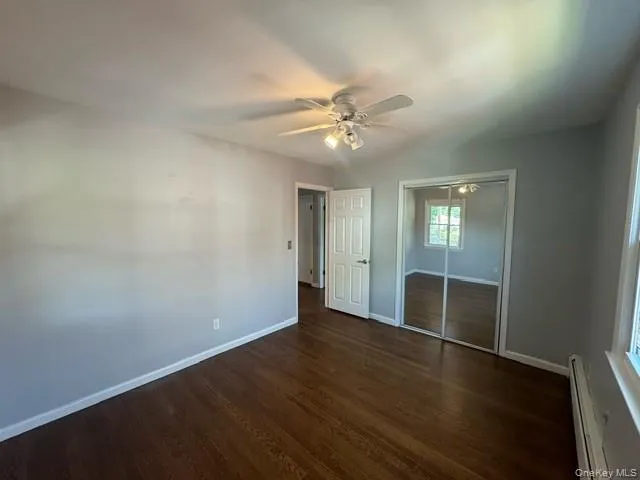 an empty room with wooden floor fan and windows
