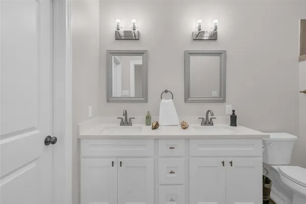 a bathroom with a double vanity sink a toilet and a mirror