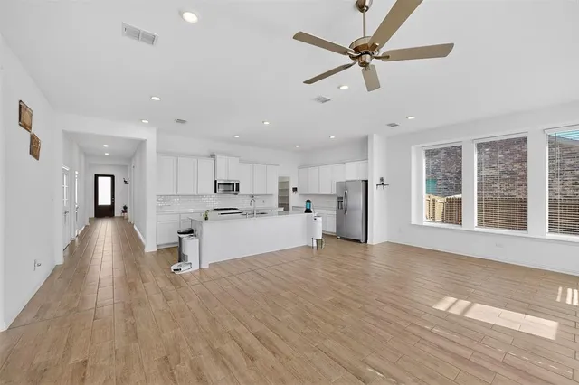 a view of a kitchen with kitchen island wooden floors appliances and furniture