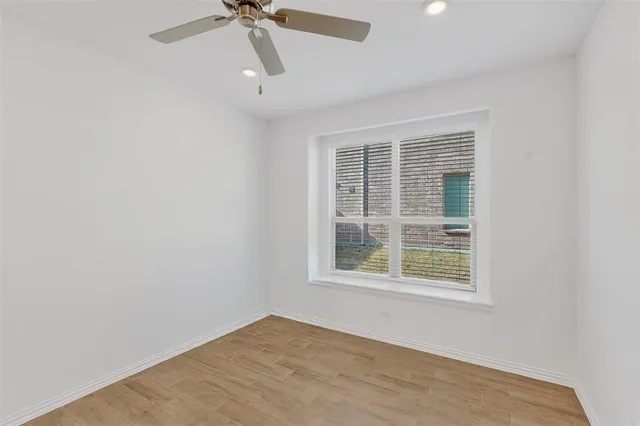 an empty room with a window and a ceiling fan