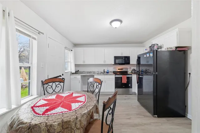 a kitchen with stainless steel appliances granite countertop a refrigerator a stove a sink a dining table and chairs