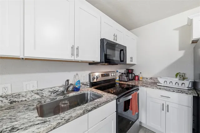 a kitchen with stainless steel appliances granite countertop a sink a stove a microwave and cabinets