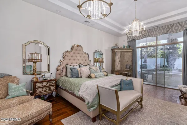 a bedroom with a bed a chandelier furniture and a large window