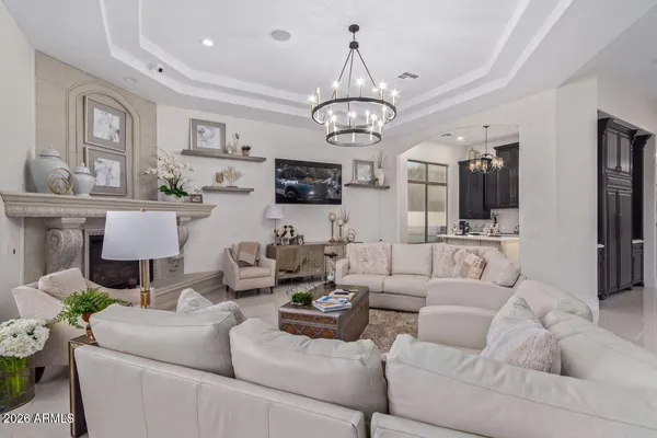 a living room with furniture kitchen view and a chandelier