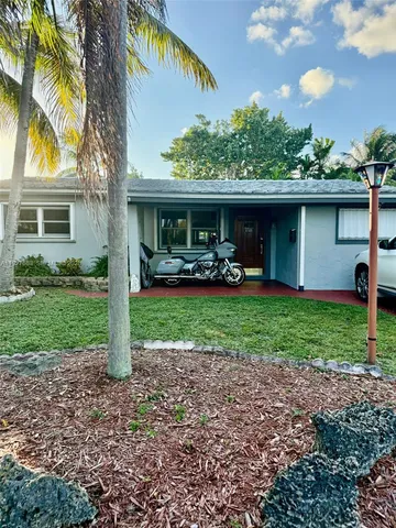 a view of a house with a yard and palm trees