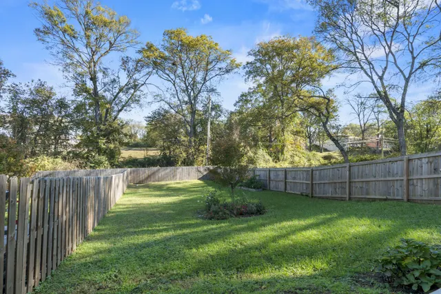 a view of backyard with barbeque grill and wooden fence