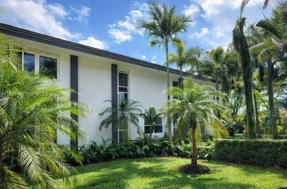 a palm tree sitting in front of a house with a yard