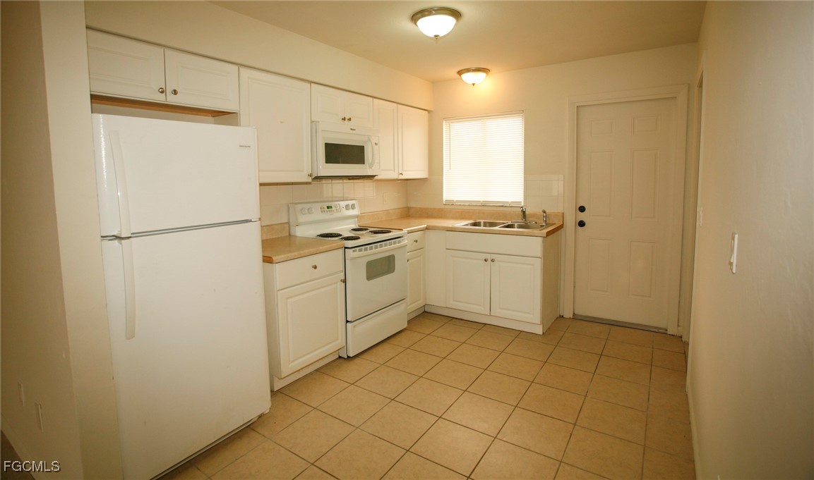 122 Gordon Avenue South Lehigh Acres, FL 33973 - Photo 5 of 12 a kitchen with white cabinets and white appliances