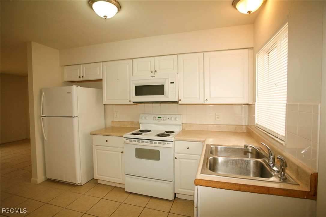 122 Gordon Avenue South Lehigh Acres, FL 33973 - Photo 6 of 12 a kitchen with white cabinets and white appliances