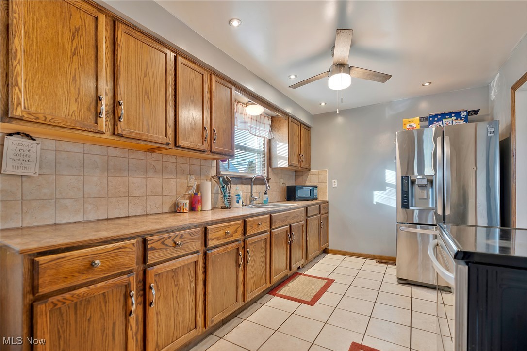 1361 Crescent Road Southwest Canton, OH 44710 - Photo 13 of 36 Kitchen with backsplash, appliances with stainless steel finishes, brown cabinets, light countertops, and light tile patterned floors