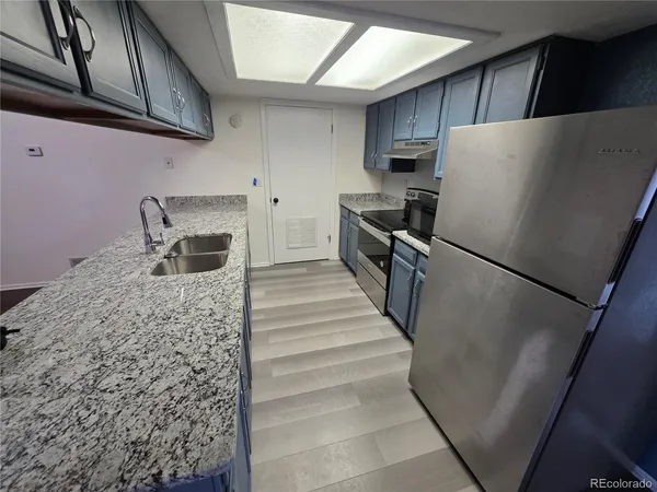 a kitchen with granite countertop a refrigerator and a sink