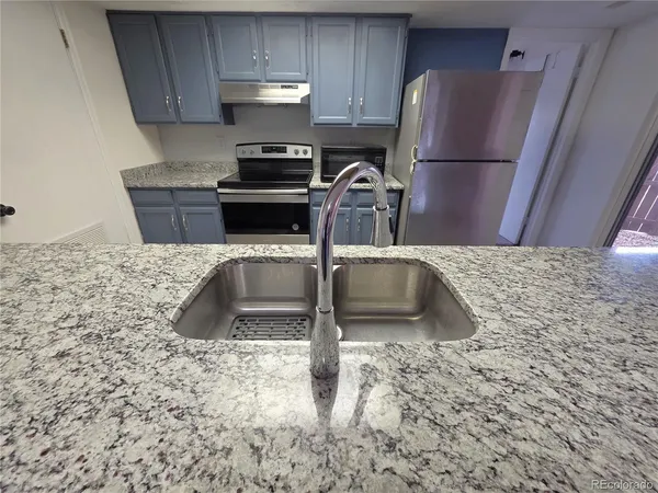 a kitchen with granite countertop a sink a stove and a refrigerator