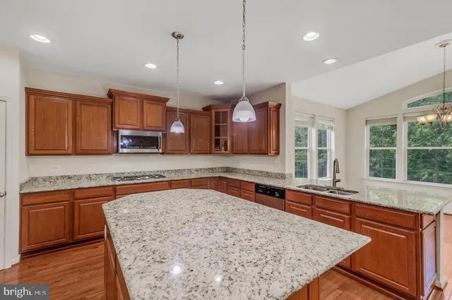 a large kitchen with stainless steel appliances granite countertop plenty wooden cabinets counter space and a window