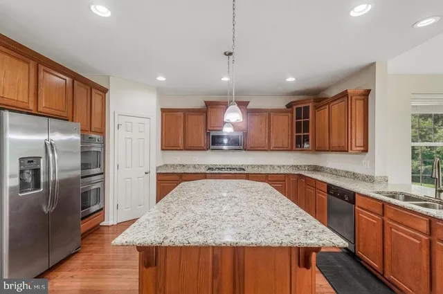 a large kitchen with granite countertop a large counter top stainless steel appliances and cabinets