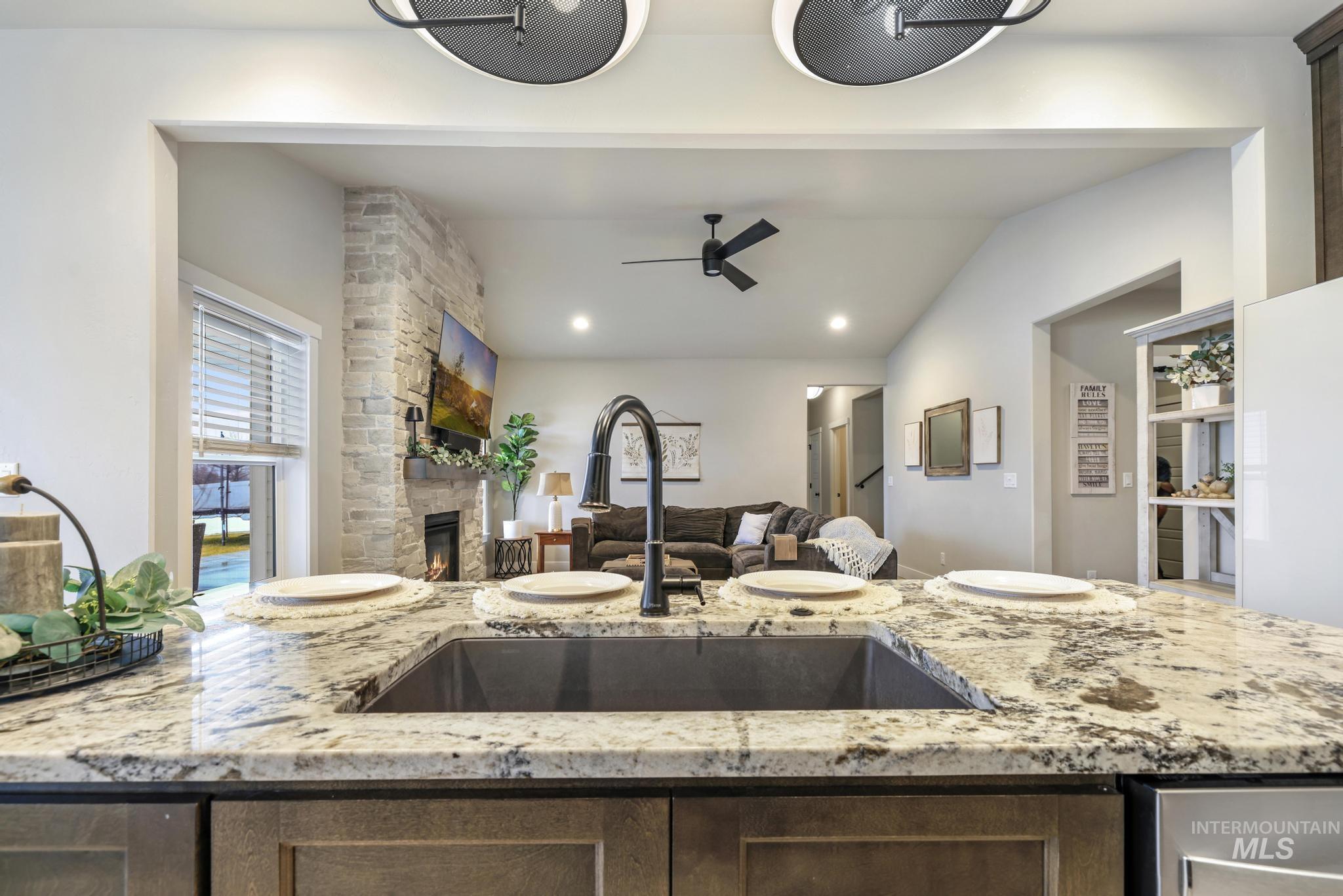 3103 Moonrise Road Twin Falls, ID 83301 - Photo 10 of 42 Kitchen with light stone counters, a stone fireplace, vaulted ceiling, ceiling fan, and recessed lighting